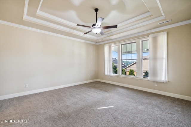 empty room featuring crown molding, carpet flooring, ceiling fan, a raised ceiling, and visible vents