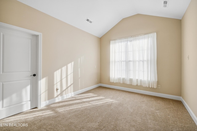 carpeted empty room with baseboards, vaulted ceiling, and visible vents