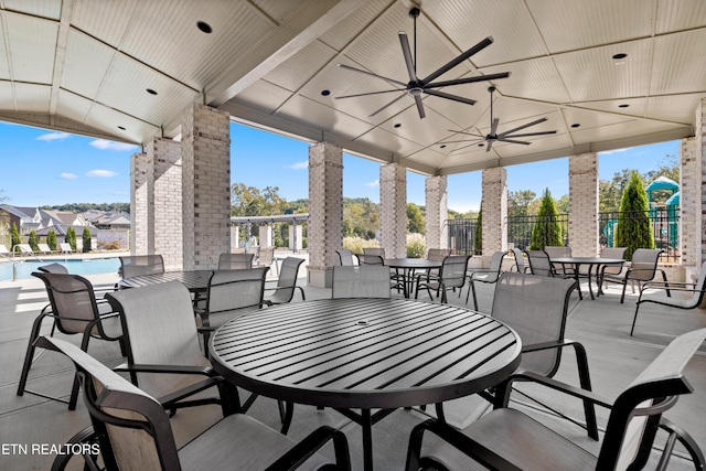 view of patio with a community pool, fence, a ceiling fan, and outdoor dining space