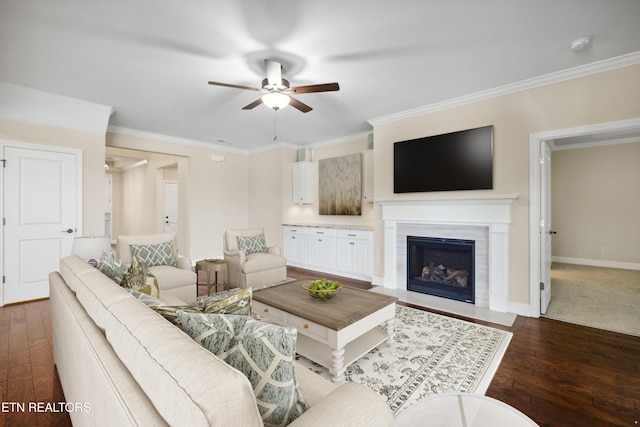 living room featuring a ceiling fan, a fireplace with flush hearth, baseboards, ornamental molding, and hardwood / wood-style floors