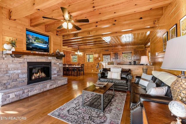 living room featuring a ceiling fan, wood walls, beamed ceiling, wood-type flooring, and wooden ceiling