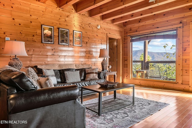 living room featuring a mountain view, wooden walls, wood-type flooring, and beam ceiling