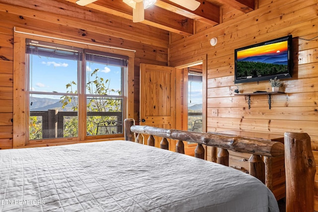 bedroom with wooden walls, beam ceiling, and multiple windows