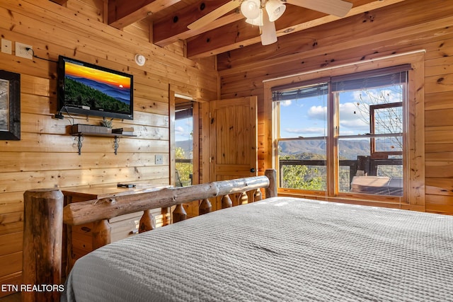 bedroom with wooden walls, beamed ceiling, and multiple windows