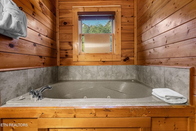 full bath featuring a jetted tub and wooden walls