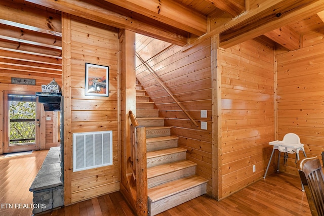 stairs with visible vents, wooden ceiling, hardwood / wood-style floors, and beamed ceiling