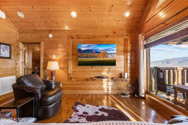 living area featuring visible vents, wood ceiling, wood finished floors, lofted ceiling, and wooden walls