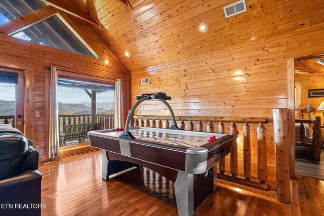 game room featuring wooden walls, visible vents, a wealth of natural light, and hardwood / wood-style floors