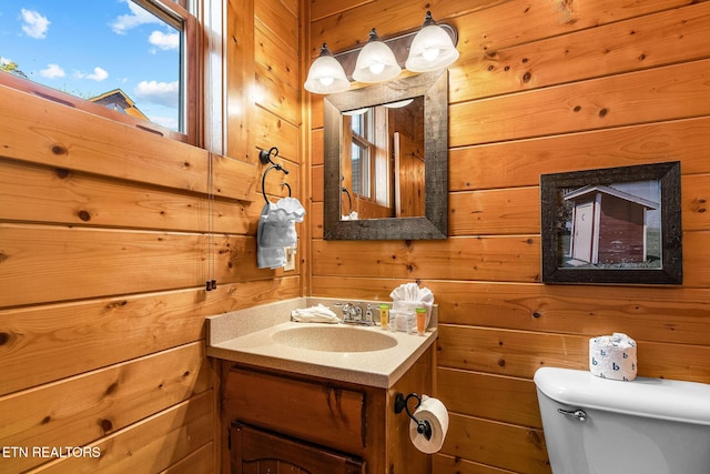bathroom featuring wood walls, vanity, and toilet