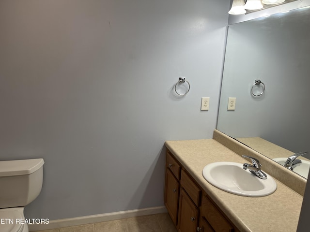 bathroom with toilet, vanity, baseboards, and tile patterned flooring