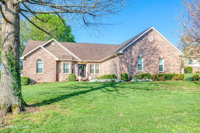ranch-style house with brick siding, a front yard, and a shingled roof