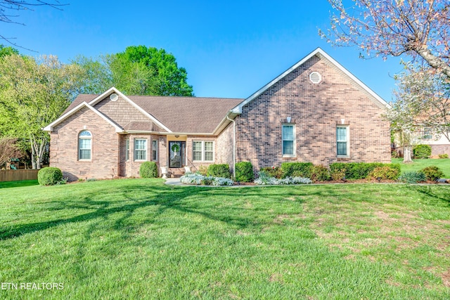 single story home featuring brick siding, a front yard, and roof with shingles