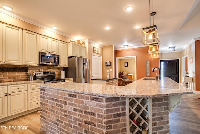 kitchen with a large island, a sink, appliances with stainless steel finishes, crown molding, and cream cabinetry
