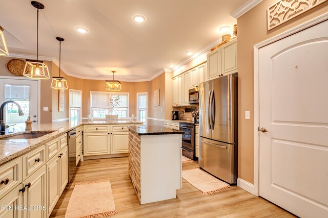 kitchen with light wood-type flooring, stone counters, appliances with stainless steel finishes, a sink, and hanging light fixtures