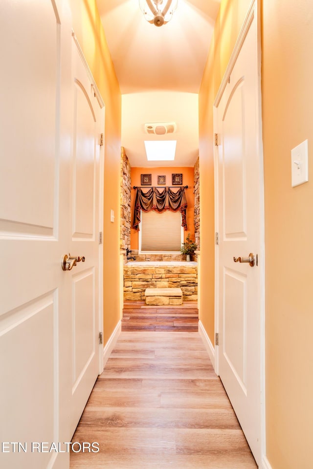 hall featuring baseboards and light wood-type flooring