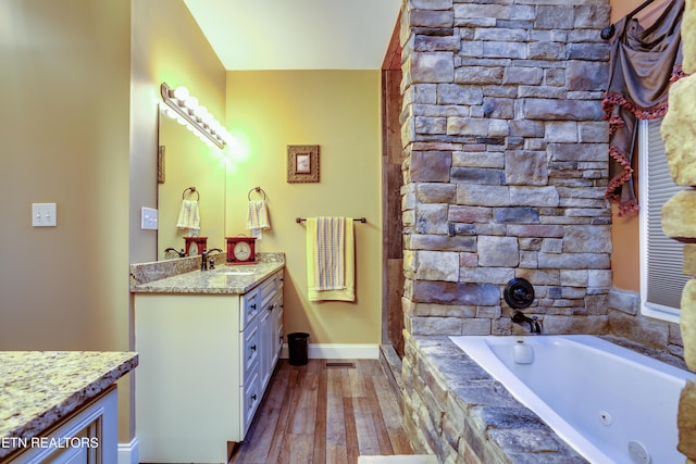 bathroom with vanity, a bath, baseboards, and wood finished floors