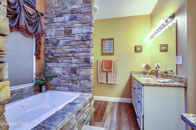 bathroom featuring a whirlpool tub, baseboards, vanity, and wood finished floors
