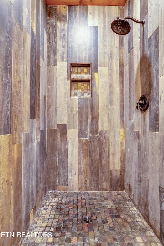 full bathroom with wooden walls and a tile shower