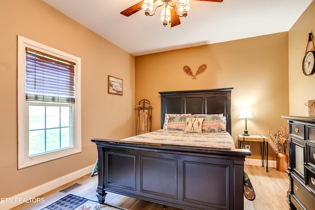 bedroom with ceiling fan, visible vents, baseboards, and light wood-style flooring