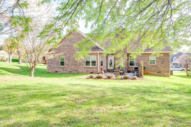 back of house featuring brick siding, a yard, a patio, and crawl space