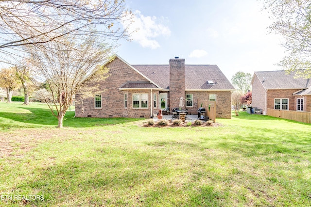 rear view of property with a patio area, brick siding, a chimney, and a lawn