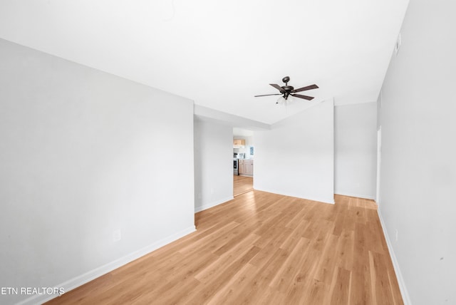 empty room with vaulted ceiling, light wood-style flooring, baseboards, and a ceiling fan