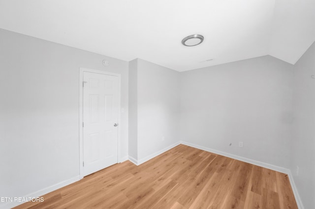 unfurnished room with light wood-style floors, baseboards, and lofted ceiling