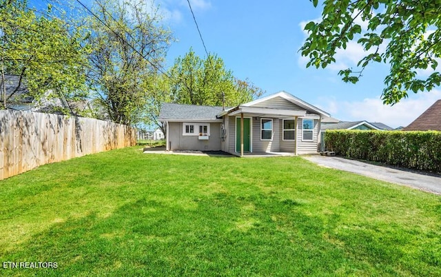 rear view of house with fence and a lawn