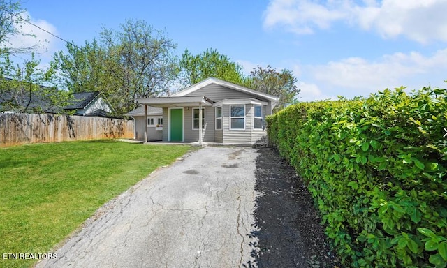 bungalow featuring driveway, fence, and a front lawn