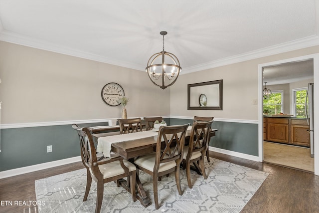 dining area featuring crown molding, baseboards, wood finished floors, and a notable chandelier