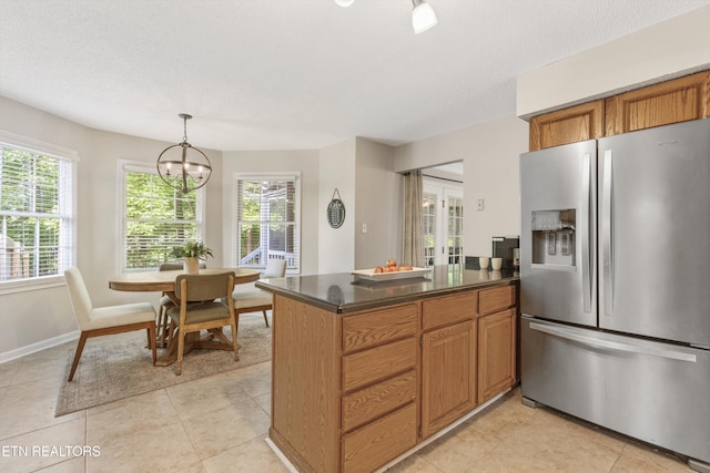 kitchen with plenty of natural light, a peninsula, dark countertops, and stainless steel fridge with ice dispenser
