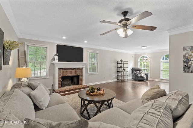 living area featuring ornamental molding, a fireplace, a ceiling fan, and wood finished floors