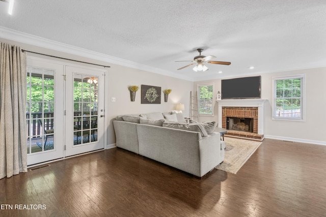 living area featuring crown molding, dark wood-style flooring, a textured ceiling, plenty of natural light, and visible vents