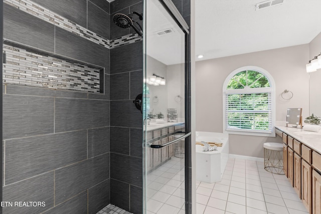 bathroom with vanity, a soaking tub, tiled shower, and visible vents