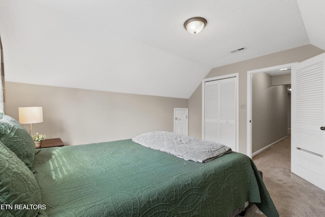 carpeted bedroom featuring visible vents, baseboards, vaulted ceiling, and a closet