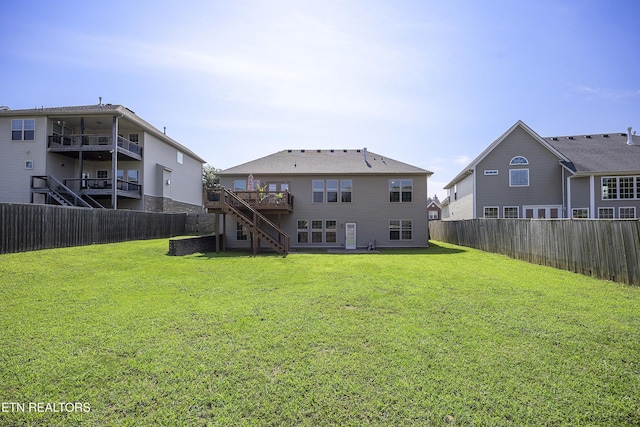 rear view of house featuring a yard, a fenced backyard, a deck, and stairs