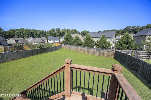 wooden terrace with a residential view, a fenced backyard, and a yard