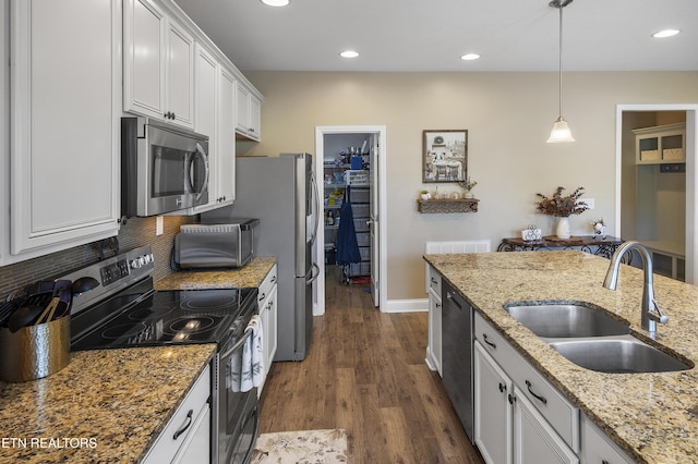 kitchen with a sink, appliances with stainless steel finishes, dark wood-style floors, recessed lighting, and white cabinetry