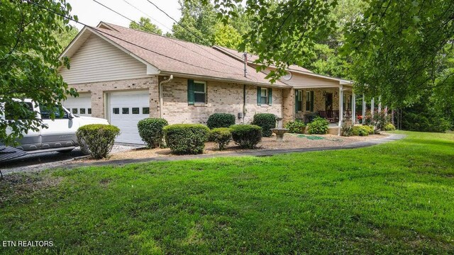 ranch-style house with a front yard, an attached garage, a shingled roof, and brick siding