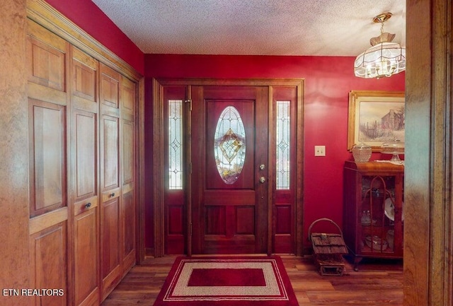 foyer with a chandelier, a textured ceiling, and wood finished floors
