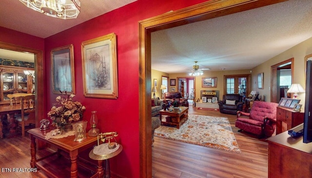 interior space featuring ceiling fan with notable chandelier, wood finished floors, and a textured ceiling