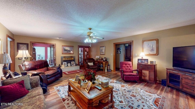 living room featuring a ceiling fan, wood finished floors, and a textured ceiling