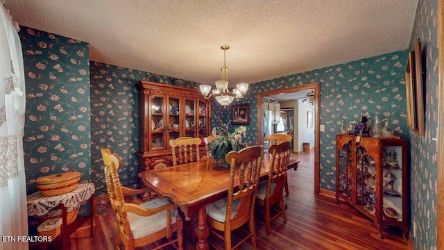 dining room featuring wallpapered walls, a textured ceiling, an inviting chandelier, and wood finished floors