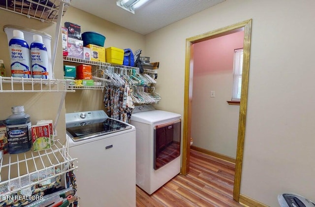 washroom with light wood-style floors, separate washer and dryer, laundry area, and baseboards