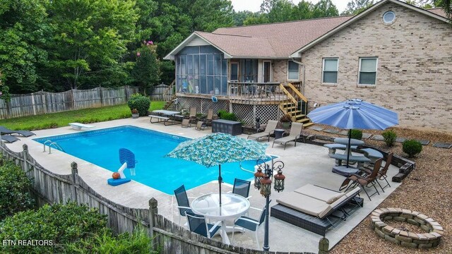 view of swimming pool with a fenced backyard, a wooden deck, a patio, and a sunroom