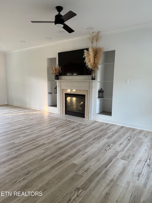 unfurnished living room featuring a glass covered fireplace, baseboards, ornamental molding, a ceiling fan, and wood finished floors