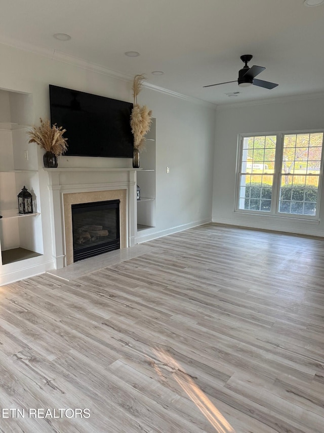 unfurnished living room with a fireplace, crown molding, a ceiling fan, and wood finished floors