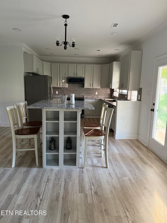 kitchen featuring light stone counters, light wood-style flooring, extractor fan, a kitchen bar, and decorative backsplash