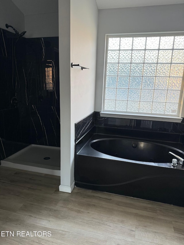 full bathroom with a bath, a marble finish shower, and wood finished floors