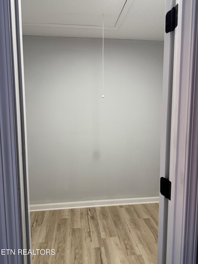 walk in closet with attic access and light wood-style floors
